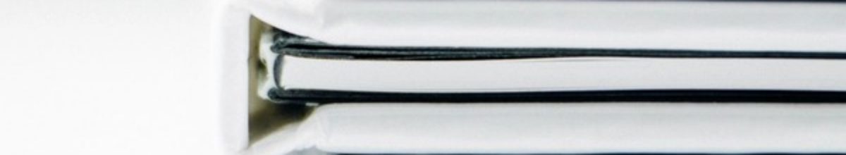 Close view of the spines of white ring binders stacked one on another.