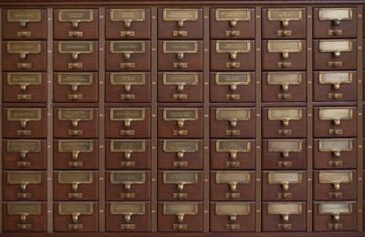 A wall of small wooden index drawers with brass label holders and handles.